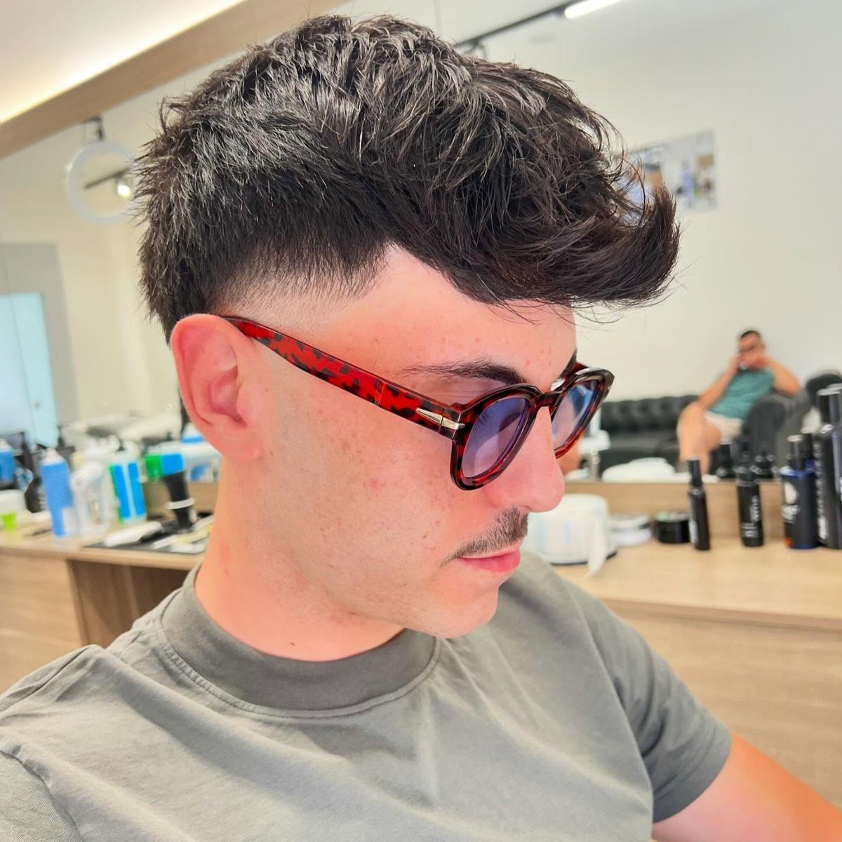 Mid fade e frangia spettinata in avanti, con gli occhiali da sole